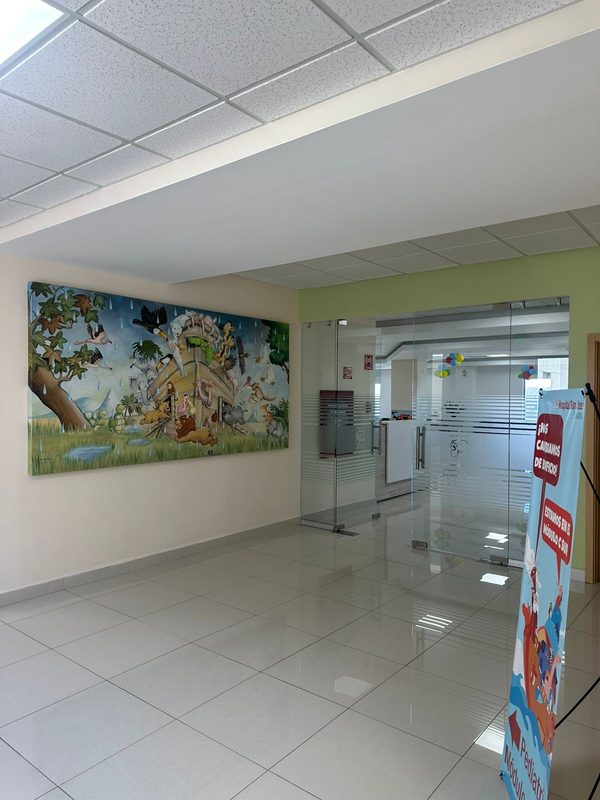 Entrada de cristal al área de pediatría del Hospital San José, con un mural infantil del arca de Noé en la pared contigua.